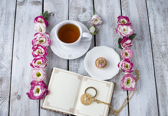 Obraz na płótnie Canvas Bouquet of beautiful flowers with cup of tea, cake and book, magnifier. Holidays background: March 8, valentine's day, mother's day, wedding, engagement