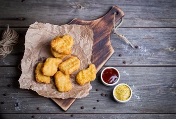 Gartenposter Wooden board with tasty chicken nuggets and sauces on table © sun_time