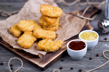 Wooden board with tasty chicken nuggets and sauces