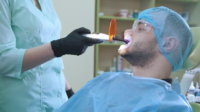 Doctor and patient in the dental office, polymerisation of fillings with a orange protective screen