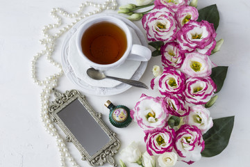 Bouquet of beautiful flowers with cup of tea and mirror with beautiful pearl necklace and fragrance. Holidays background: March 8, valentine's day, mother's day, wedding, engagement
