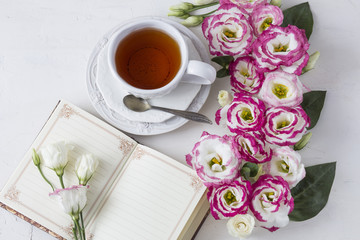 Bouquet of beautiful flowers with cup of tea and book. Holidays background: March 8, valentine's day, mother's day, wedding, engagement