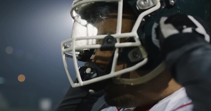 American football player puts his helmet with lights in background