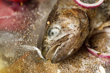 Fresh fish with spices and onion on aluminum foil, closeup