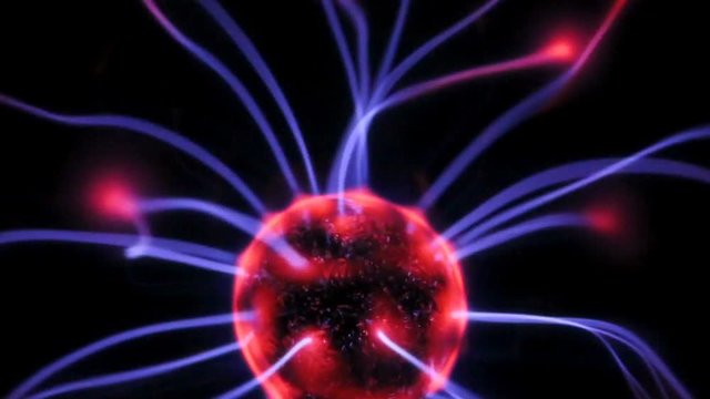 Plasma globe with red and blue arcs close up against a black background