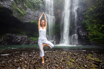 Woman practices yoga near Sekumpul waterfall in Bali, Indonesia