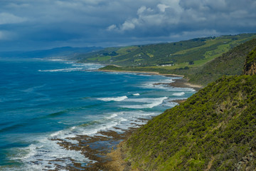 Fototapeta na wymiar Australian coastline with crashing waves and green hills