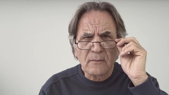 Elder man looking detail, holding glasses