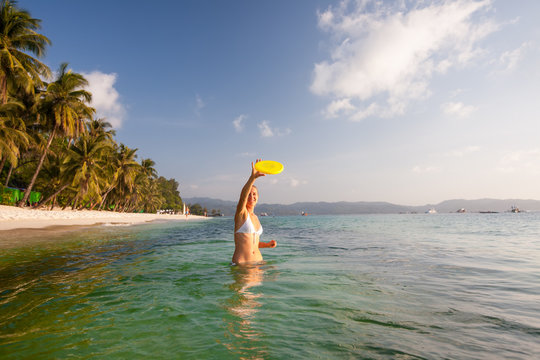 Woman plays frisbee in the water of beautiful ocean - Powered by Adobe