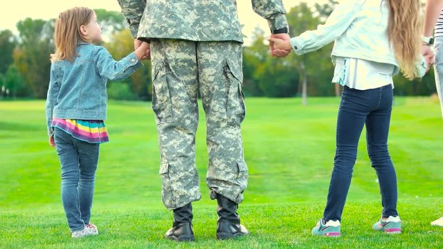 Two daughters of a soldier. Close up back view military father with kids standing together.