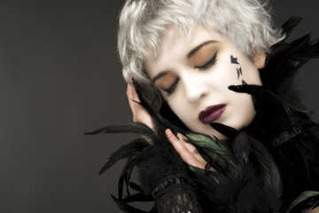 Androgynous witch girl with red-green eyes and black feathers