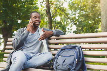 Fototapeta premium Smiling african-american student talking on the phone outdoors