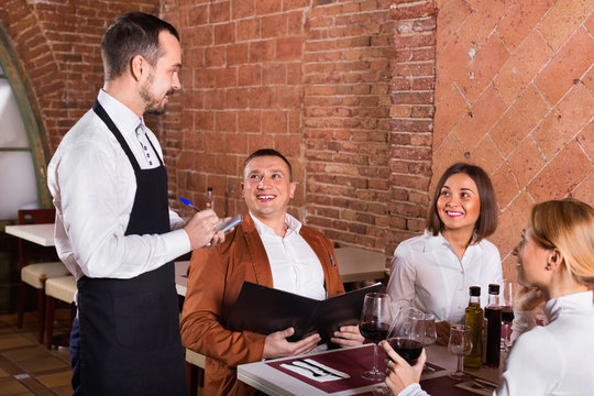 Male waiter taking order from visitors