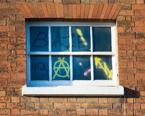window with graffiti and anarchy signs with brick surround