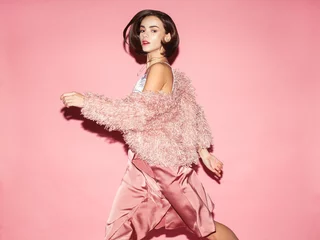 Poster young fashion woman in pink clothes run on pink background © Sergey Chumakov