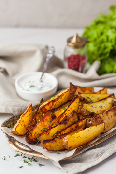 Delicious roasted potatoes garnished with parsley. Baked potato slices with sour cream sauce on a tray