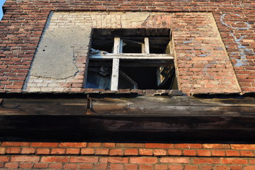 Stare okno. Widok z dołu na stare okno w ceglanym domku. Okno jest zniszczone bez szyb.  - obrazy, fototapety, plakaty