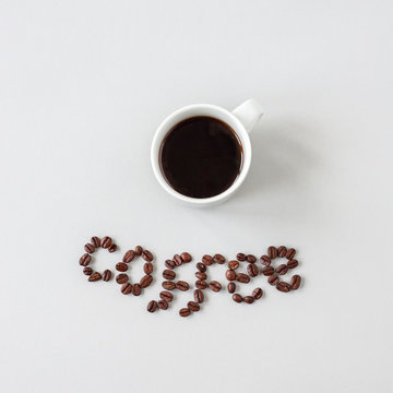 Fototapeta Coffee word made of coffee beans and cup of coffee, top view