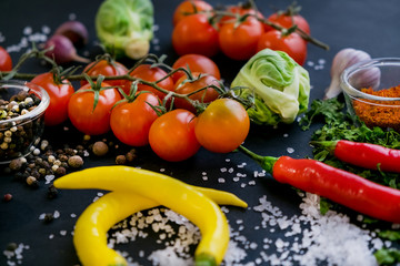 Close up of colorful spices and fresh vegetables for cooking on dark metal background with space for text. Top view. Bio Healthy food ingredients.