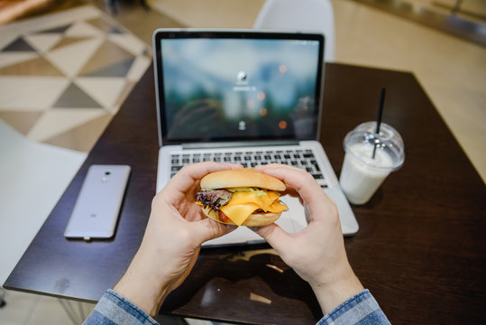 man eat burger in cafe and work on laptop