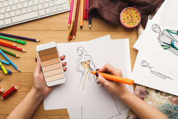 Top view on woman designer drawing clothes sketches