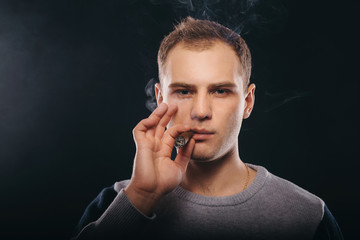 brutal man smoking a cigar and blowing smoke on a black background