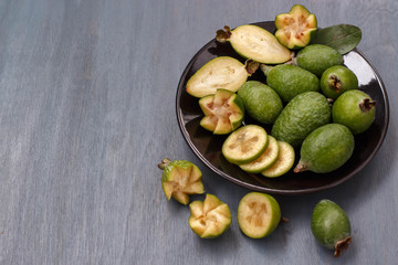 white plate with feijoa fruits on dark blue wooden background
