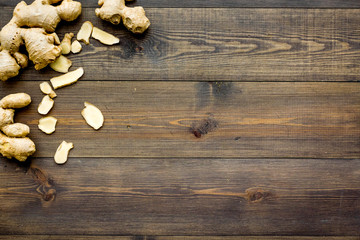 Whole and sliced ginger roots on dark wooden background top view space for text