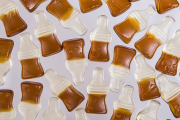 Chewing marmalade bottles of cola on light background. - 191896864