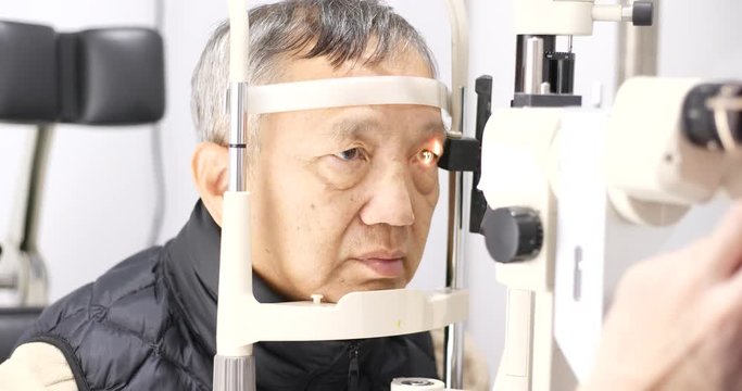 Old man checking on eye in clinic