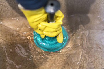 Cleaning the sink. Yellow protective glove