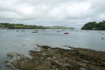 Fototapeta na wymiar Looking across the Helford Estuary from the village of Helford at the many small boats at moorings around Helford Passage, Cornwall, UK