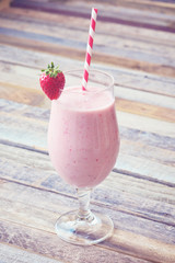 Delicious strawberry smoothie on wooden background