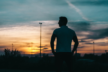 Silhouette of a young man in the sunset background
