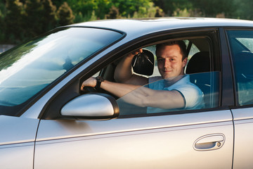 Young attractive caucasian man in white t-shirt sitting in the car