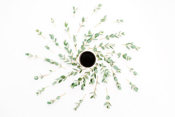 Cup of coffee in frame of eucalyptus branch on white background. Flat lay, top view minimal composition.