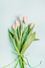 Pastel pink tulip flowers bouquet on pale blue background. Flat lay, top view. Minimal spring floral concept.