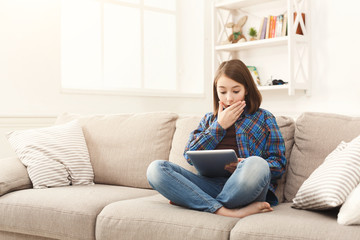 Young shocked girl with digital tablet at home