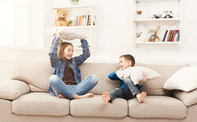 Obraz premium Brother and sister having pillow fight on sofa