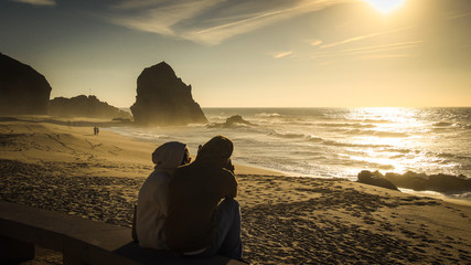 couple of lovers at sunset on a beach with rocks in the background. Portugal