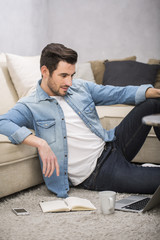 Fototapeta premium Attractive man in living room with laptop
