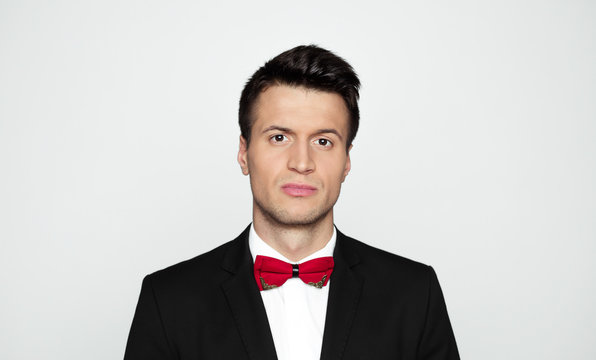 Have a good day! Close up portrait of smiling stylish handsome man in black suit and red bow tie isolated.