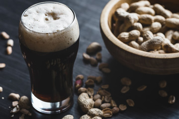 Glass of beer and peanuts on the wooden background