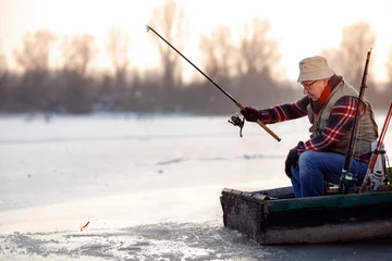 Zelfklevend Fotobehang elderly man fishing in the winter on the lake © luckybusiness