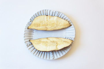Two halves of a goguma Korean yam on a white plate, centered, isolated on white, food ingredient, horizontal aspect