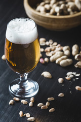 Glass of beer and peanuts on the wooden background