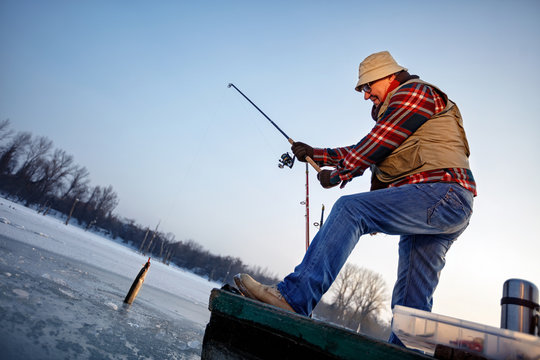 Fisherman catch fish on the frozen river in winter
