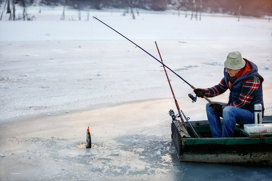 Ice fishing on frozen lake- fisherman fishing on ice