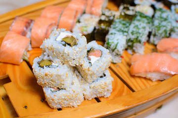 many kinds of sushi on a wooden stand in the form of a ship