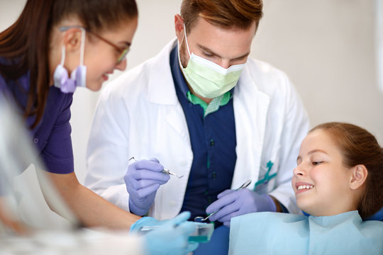 Female assistant with male dentist repairing child's teeth
